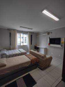 a bedroom with two beds and a flat screen tv at Apto studio 302 centro de Florianópolis in Florianópolis