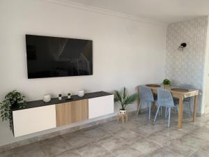 un soggiorno con un tavolo e una TV a parete di Casa 3 Soles a Morro del Jable Altre 50 foto