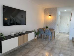 un soggiorno con tavolo e TV a parete di Casa 3 Soles a Morro del Jable