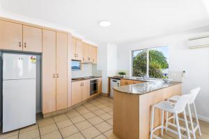 a kitchen with wooden cabinets and a white refrigerator at 'Villa Mar Colina U12' Coastal Escape, Yeppoon in Yeppoon