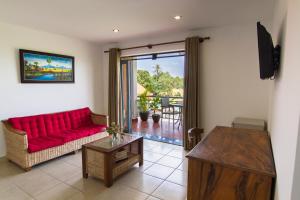 a living room with a red couch and a table at Le Kroma Villa in Phumĭ Prêk