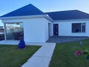 a white house with a window and a yard at Ferry Lodge Cottage in Kilrush