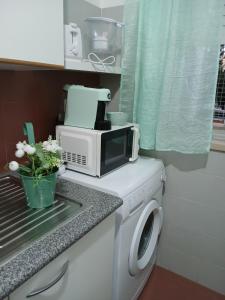 a microwave sitting on top of a washing machine at Kannon 1 in Caparica