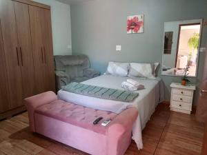 a bedroom with a bed and a pink ottoman at Studio Carimã Foz in Foz do Iguaçu