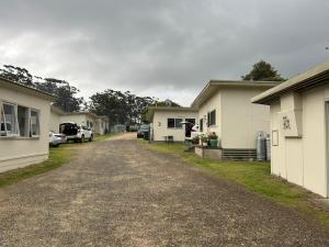 a dirt road between two houses with cars parked at Bemm River Bungalows - Bellbird Abode - Bungalow 1 in Bemm River