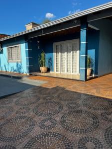 een blauw huis met een mozaïekvloer ervoor. bij Linda Casa com Piscina e Edícula Gourmet Ouro verde in Foz do Iguaçu