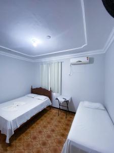 a room with two beds and a table in it at Hotel Minas Brasil in Salinas