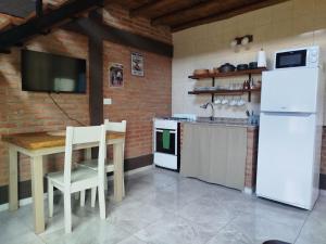 a kitchen with a table and a white refrigerator at Kuntur Casas de Campo in Mina Clavero +27 photos