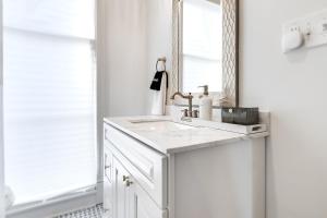 a white bathroom with a sink and a mirror at Nesting Escapes at Abercorn in Savannah +56 photos
