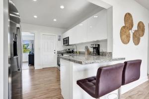 a kitchen with white walls and a counter and chairs at Villa Riviera Beach -4Bdr Relaxing Retreat By Viac in Riviera Beach +45 photos