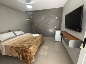 a bedroom with a bed and a flat screen tv at Cantinho da Ilha Suites in Abraão