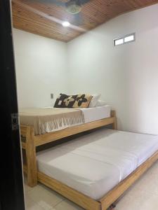 Dos camas en una habitación con paredes blancas y techos de madera. en Hospedaje LunaDorada en Doradal, en Puerto Triunfo