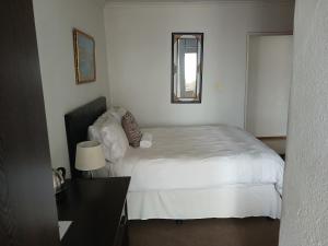 a bedroom with a white bed and a mirror at Moshitametsi Guesthouse in Kempton Park