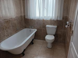 a bathroom with a tub and a toilet and a sink at Moshitametsi Guesthouse in Kempton Park +6 photos