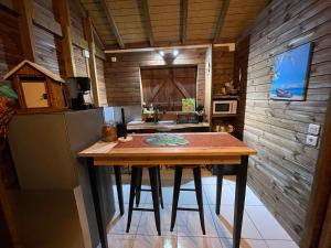 a kitchen with a table and a refrigerator at LES HAUTS DE L'ANSE in Bouillante