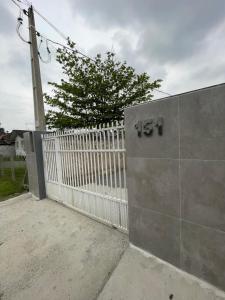 a white picket fence next to a white gate at Mini Casa 5 in Itajaí +1 photo