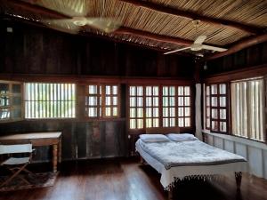 a bedroom with a bed and a desk and windows at Casa Nalu in San Juan del Sur