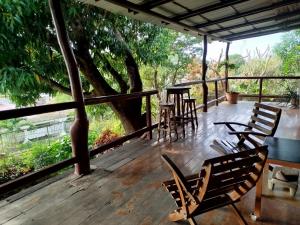 a porch with chairs and tables and a tree at Casa Nalu in San Juan del Sur