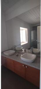 a bathroom with three sinks and a large mirror at Casona Starlight in Melipilla