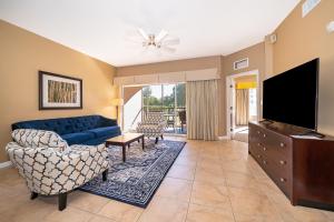 ein Wohnzimmer mit einer blauen Couch und einem Fernseher in der Unterkunft Pura Vida a Private Master Bedroom with shared living space in Orlando