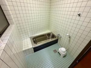 a tiled bathroom with a toilet in a stall at Nomad Kumano in Nachikatsuura