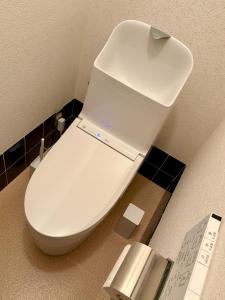a white toilet in a bathroom with black tiles at Nomad Kumano in Nachikatsuura