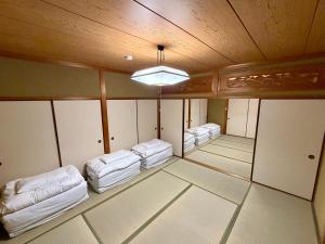 an empty room with white beds and a wooden ceiling at Nomad Kumano in Nachikatsuura