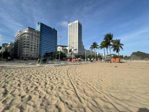 a sandy beach with buildings and palm trees in a city at 3 min da Praia de Copacabana - Apartamento Compartilhado PR in Rio de Janeiro