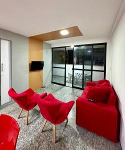 205 Atlântico Residence Vista Mar في فورتاليزا: غرفة معيشة مع أريكة حمراء وكراسي