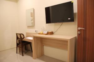 a room with a desk with a television on a wall at M3 Sanur Hotel in Sanur