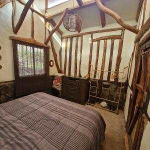 a bedroom with a bed in a room with beams at Refugio de montaña OM in Santiago