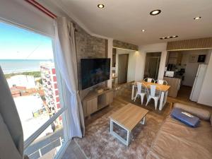 a living room with a table and a large window at Chiara's Apartament panoramico in Santa Teresita