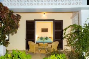 a patio with a table and chairs and a bed at La maison bleue BTB in Phumĭ Kâmpóng Âmpĭl