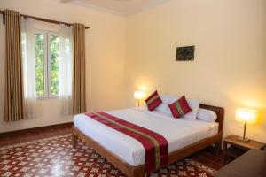 a bedroom with a bed with two lamps and a window at La maison bleue BTB in Phumĭ Kâmpóng Âmpĭl +28 photos