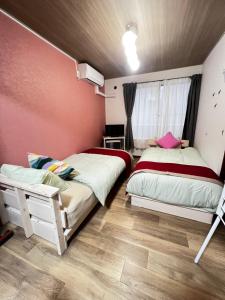 2 letti in una camera con pareti rosa e pavimenti in legno di サイプレス平岸 a Sapporo