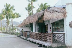 a restaurant with a thatched roof and palm trees at Bay's Inn Resort in Baler