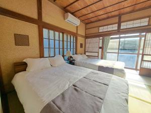 a bedroom with two beds and a large window at 不入斗-横須賀の大型一棟貸し-最大25人-家族団体向け in Yokosuka