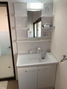 a white bathroom with a sink and a mirror at 不入斗-横須賀の大型一棟貸し-最大25人-家族団体向け in Yokosuka