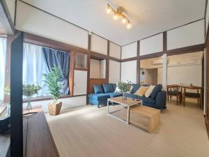 a living room with a blue couch and a table at 不入斗-横須賀の大型一棟貸し-最大25人-家族団体向け in Yokosuka