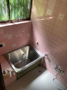 a pink tiled bathroom with a sink and a window at 西逸見 in Yokosuka +19 photos
