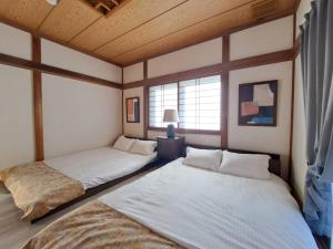 two beds in a room with wooden ceilings at 西逸見 in Yokosuka