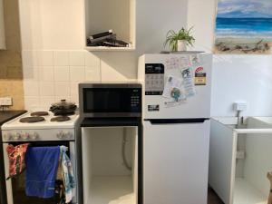 a kitchen with a white refrigerator and a stove at Beach front apartment in Batemans Bay