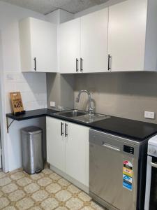 a kitchen with white cabinets and a sink at Beach front apartment in Batemans Bay