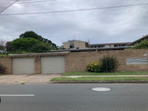 a brick house with two garage doors on a street at Beach front apartment in Batemans Bay +8 photos
