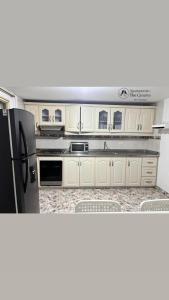 a kitchen with white cabinets and a black refrigerator at Apartamento thecanarys in Santa Rosa de Cabal