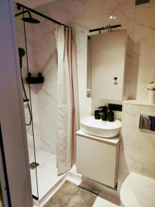 a white bathroom with a sink and a shower at Apartamentai šalia miesto centro in Telšiai