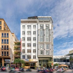 Tago Airport Hotel في مدينة هوشي منه: مبنى ابيض طويل على شارع المدينة وبه سيارات