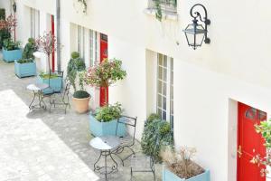 un patio con mesas y sillas y una puerta roja en Hotel Suites Unic Renoir Saint-Germain, en París