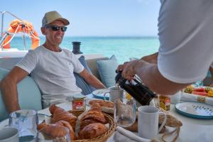 Ein Mann sitzt an einem Tisch mit einem Teller Gebäck. in der Unterkunft Catamaran Liveaboard Charters Mauritius in Rivière Noire