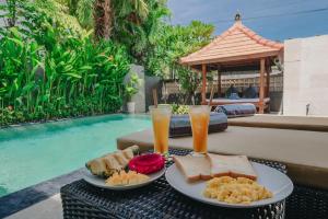 a table with two plates of food and drinks next to a pool at Villa Royal in Singaraja